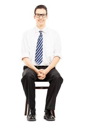 Young male with tie sitting on a wooden chair waiting for job in